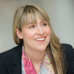 Photo of Jo Mylan wearing a pink scarf and blazer